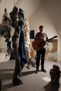 Bilde av Haakon med gitar i atelieret til Hanne Fris på frysja. Foto av Henriette Nilsson